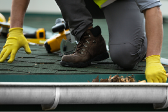 RoofEXT worker cleaning dirty gutters
